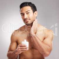Handsome young mixed race man shirtless in studio isolated against a grey background. Hispanic male applying aftershave after shaving. Take care of your skin when you groom or shave your beard and face