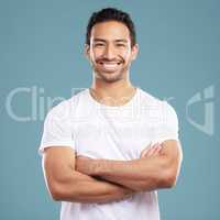 Handsome young mixed race man with his arms crossed while standing in studio isolated against a blue background. Happy hispanic male smiling while looking confident and powerful with his arms folded