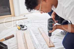 Im determined to turn this place into something beautiful. Shot of a man drilling holes into a wooden plank.