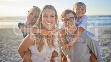 Portrait of a happy caucasian family standing together on the beach. Loving parents spending time with their two children during family vacation by the beach