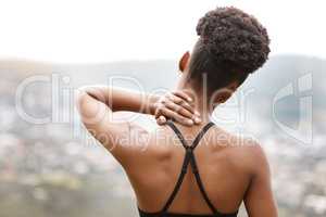 Active woman holding her neck in pain while exercising outdoors. Closeup of athlete from behind suffering with a sore body injury, causing discomfort and strain. Muscle sprain from fractured joints