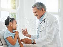 You wont feel a thing. Shot of a mature male doctor giving a little girl an injection during a checkup at home.