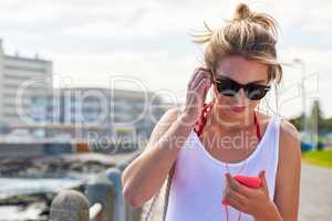 Time to pick the tune of the summer. Shot of a young woman listening to music on her smartphone.