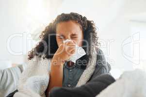 Ive got the sniffles today. Shot of a little girl blowing her nose while sick in bed at home.