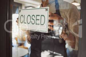 Closeup on hands of businessman hanging a closed sign. Business owner hanging a closed message in cafe door. Hands of bistro boss advertising that his shop is closed. Employee standing in entrance
