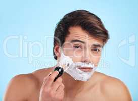 The smoother the face the smoother the man. Shot of a young man shaving his face against a studio background.