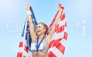 Young fit female athlete cheering and holding American flag after competing in sports. Smiling fit active sporty woman feeling motivated and celebrating achieving gold medal in olympic sport