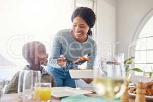 Family isnt a social construct but an instinct. Shot of a mother dishing food for her son at home.