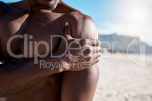 Closeup shot of an african american muscular athletic man holding his shoulder in pain. Black unrecognizable male suffering from arthritis in his arm. Suffering from a hurting, stiff, injured joint