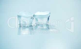 . Two ice blocks melting side by side against a blue background in studio. A symbol of global warming as an environmental risk and concern. UV protection is needed during the hot season of summer.