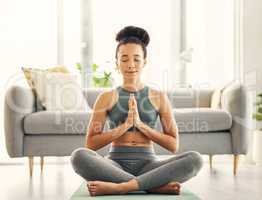 I meditate because it keeps me sane. Shot of a young woman meditating in her living room.