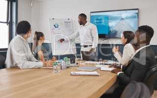 A group of young diverse corporate business people working as a team on a project in a boardroom. African American man speaker using a chart and graph to discuss statistics and planning a strategy