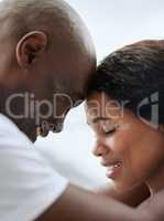 Closeup of a happy young african american couple posing with their foreheads together. Black man and woman smiling and feeling in love. Headshot of loving couple touching heads intimately with bonding