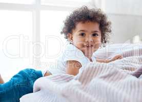 Curly cuteness overload. Shot of an adorable little girl on a bed.
