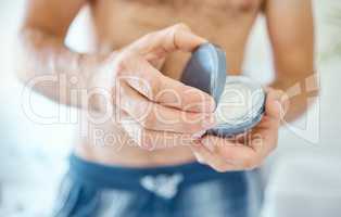 An unknown man applying cream or moisturiser to his face in a bathroom at home. One unrecognizable male using a lotion or sunscreen in his apartment