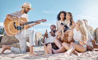 Are my friends good listeners Checked. Shot of a man playing the guitar while his friends sing along at the beach.