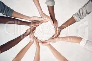 Group of businesspeople making a circle shape with their hands together in an office at work. Business professionals having fun standing with their hands joined to make a round shape in support and unity