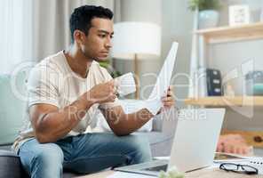 Will my savings be where I need them to be. a handsome young man sitting alone in his living room and looking contemplative while calculating his finances.