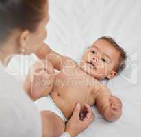 My mama, my guardian angel. a woman changing her adorable baby boys diaper at home.