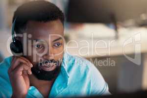 One young african american call centre telemarketing agent talking on a headset while working in an office. Focused businessman consultant operating a helpdesk for customer service support