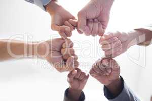 There is more power in unity than division. Shot shot of a group of unidentifiable businesspeople joining their fists together in a unity.