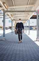 Black businessman travelling alone.A african american businessman walking around town with his luggage while wearing mask to protect himself from the corona virus in the city