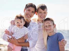 Mother with her adopted children Portrait of multiethnic family on the beach. Happy family on holiday by the ocean. Young mother on the beach with her children. Two adoptive boys with their family