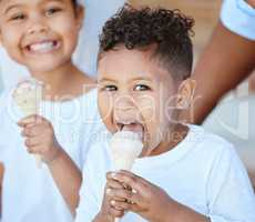 Sweet treat for sweet kids. Shot of an adorable little boy and girl eating an ice-cream cone while sitting outside.
