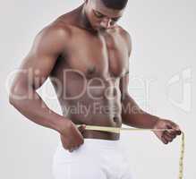 A champion is someone who gets up when they cant. a man measuring his waist using a measuring tape against a studio background.