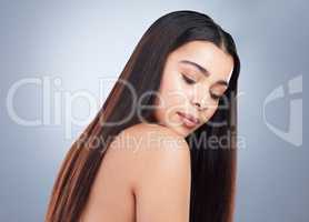 Beautiful young woman with shiny brown and straight long hair. Young girl looking down at her shoulder and showing off healthy-looking hair