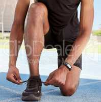 Athlete preparing for a race on the track. Closeup of an athlete fastening his sneakers to prevent tripping while getting ready for cardio training and a workout on a running track