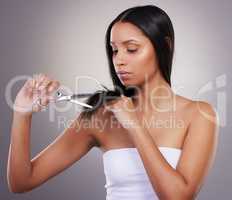 So many splitends. an attractive young woman standing alone in the studio and using scissors to trim her hair.