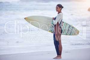 Let the waves carry you where the light cannot. Shot of an attractive young woman carrying a surfboard at the beach.