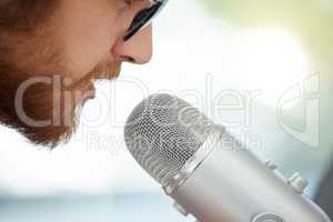 Keeping his audience updated with the latest. Closeup shot of a businessman using a microphone during a broadcast in an office.