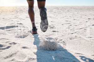Feet of one black man running and jogging on sand at the beach in the morning for exercise. Closeup of one male athlete from behind doing fast cardio workout with speed to build muscle and endurance