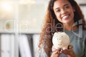 Beautiful young african american woman presenting her piggyback while standing in the living room it at home. Happy mixed race person smiling while planning, saving and investing for a bright future