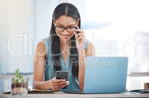 Smiling ambitious mixed race businesswoman sitting alone at a desk in the office and browsing the internet on her cellphone. Hispanic professional using technology to connect and network with clients