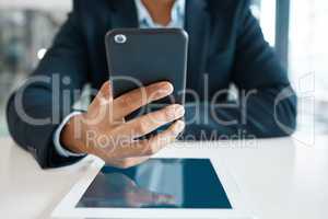 Closeup of a mixed race businessman holding and working on a phone alone at work. One hispanic male businessperson using social media on a cellphone in an office at work