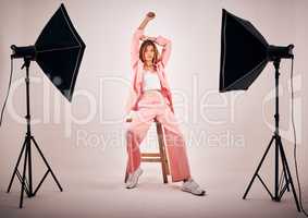 Portrait of a young mixed race female posing in trendy fashionable clothing while chilling on a chair in a studio shoot. Hispanic woman showing the latest fashion collection with a cool style and pose