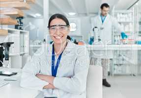 Science is the world I love getting lost in. Portrait of a young scientist sitting with her arms crossed in a lab.