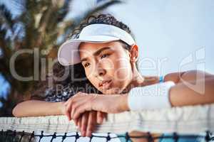 Ill never be the champion if I keep losing. Shot of an attractive young woman leaning on a tennis net and looking disappointed after practice.