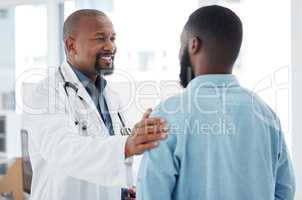Mature doctor giving a patient support. African american doctor touching a patient on the arm. Patient in a consult with his doctor. Caring doctor giving a patient comfort and support.