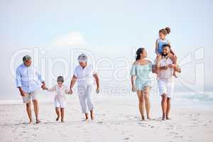 Multi generation family on vacation walking along the beach together. Mixed race family with two children, two parents and grandparents spending time together by the sea