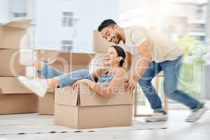 Caught up in a whirlwind of excitement. Shot of a young couple playing with boxes while moving house.