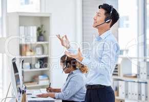 Confident asian customer service rep standing and talking on headset in office. Man working in call center consulting and operating a helpdesk for customer sales and service support