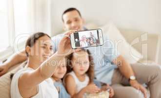 Capture the moment and itll live forever. a woman taking a selfie at home with her family.