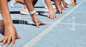 Closeup of determined group of athletes in starting position line to begin sprint or run race on sports track stadium. Hands of diverse sports people ready to compete in track and field olympic event