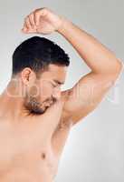 Oh no, thats disgusting. Studio shot of a handsome young man looking disgusted by his smelly armpits while posing against a grey background.