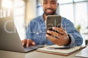 Businessman sending a text message on his smartphone at home. Young entrepreneur using his cellphone to read a message. Always online with his wireless device. Keeping connected to the internet