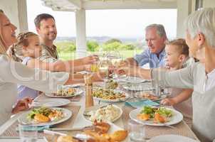 Remember to make eye contact. Shot of a family toasting during a sunday lunch.